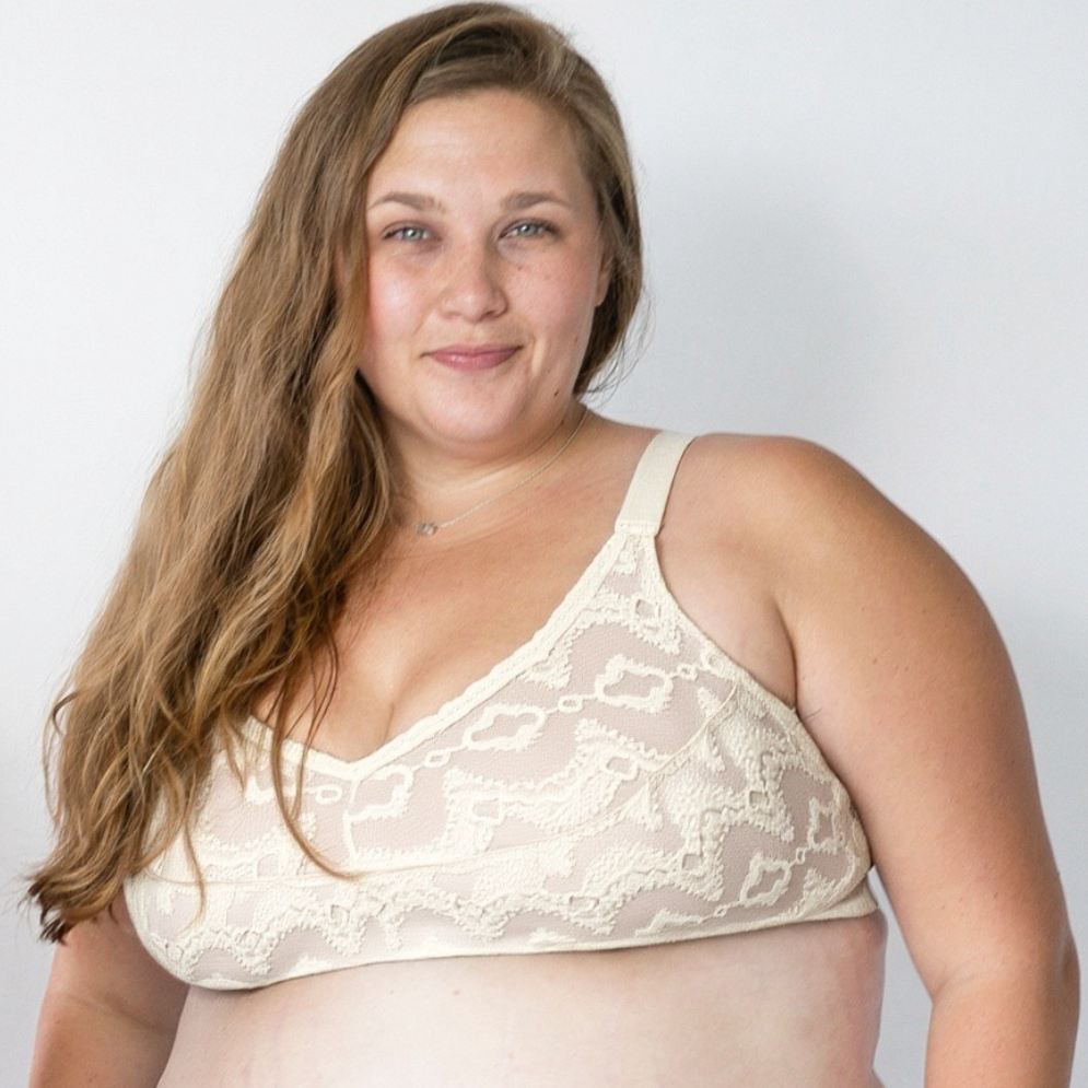 Woman wearing a beige lace bralette against a plain background